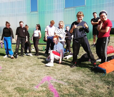 A line of dance students on the grass  showing their muddy clothes to the camera