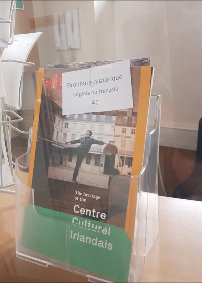 Image of a brochure on a reception desk.  The brochure has a picture of a man (Fearghus) dancing in the courtyard of a n 18th century French building