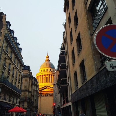 Image of the Pantheon Paris Dome caught by the evening sun, seen at the end of a narrowing street 