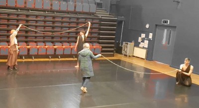 Two pairs of people in a dance studio holding a string of pearls between them